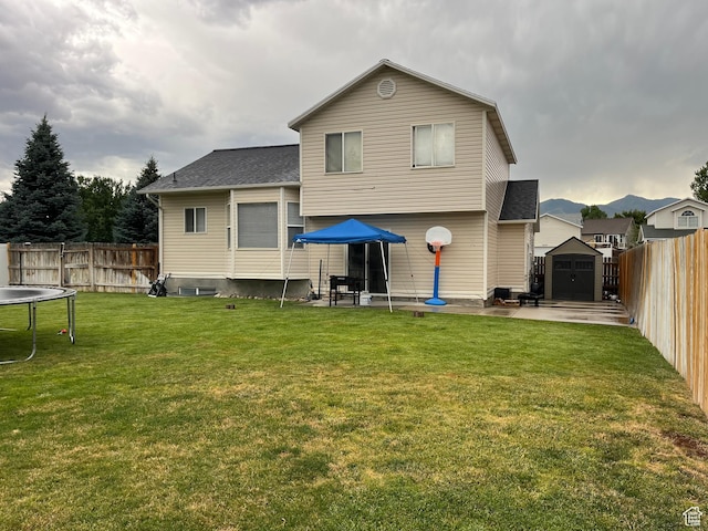 6433 S Laurel Canyon Dr W, Salt Lake City, UT 84118 - rear view of house with a trampoline, a shed, a fenced backyard, a patio area, and roof with shingles