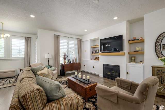 10465 S Beetdigger Blvd, Sandy, UT 84070 - living room with a textured ceiling, wood finished floors, a glass covered fireplace, built in shelves, and recessed lighting