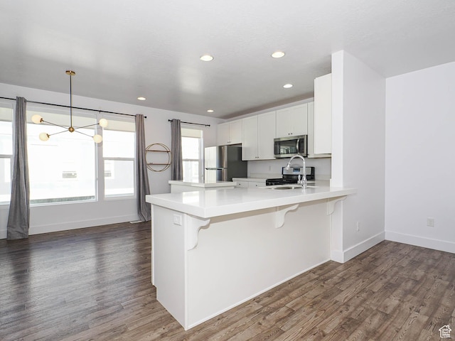 1792 W Dalmeny Way, Riverton, UT 84065 - kitchen with stainless steel appliances, a chandelier, a peninsula, a kitchen breakfast bar, and dark wood-type flooring