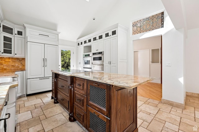 4307 Churchill Dr N Unit 97, Provo, UT 84604 - kitchen featuring paneled fridge, stone tile flooring, backsplash, white cabinetry, and high vaulted ceiling