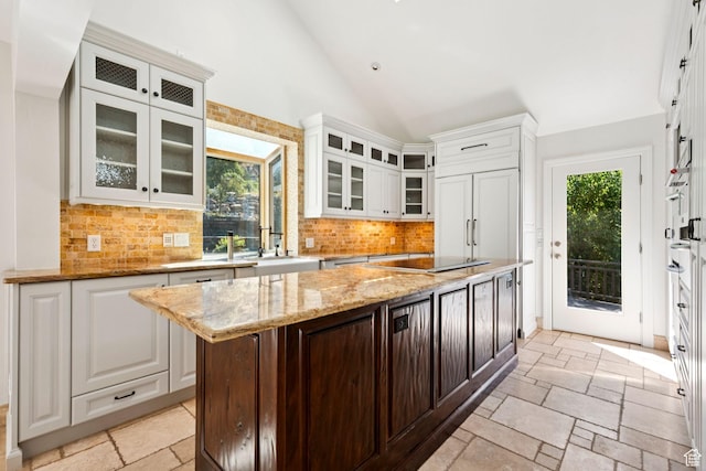 4307 Churchill Dr N Unit 97, Provo, UT 84604 - kitchen featuring black electric stovetop, stone tile flooring, white cabinetry, vaulted ceiling, and tasteful backsplash
