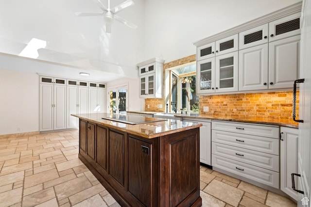 4307 Churchill Dr N Unit 97, Provo, UT 84604 - kitchen featuring a towering ceiling, stone tile flooring, tasteful backsplash, and white cabinets