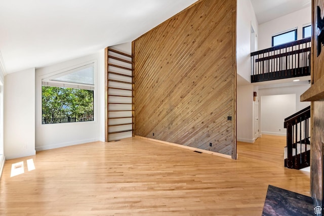 4307 Churchill Dr N Unit 97, Provo, UT 84604 - unfurnished living room featuring wood walls, light wood-type flooring, a towering ceiling, and stairs