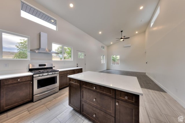 1191 Wagner Ave, Moab, UT 84532 - kitchen with stainless steel gas range oven, wall chimney range hood, a ceiling fan, light countertops, and dark brown cabinetry