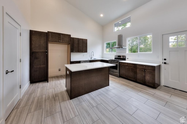 1191 Wagner Ave, Moab, UT 84532 - kitchen featuring stainless steel range with gas cooktop, wall chimney range hood, high vaulted ceiling, dark brown cabinetry, and light countertops