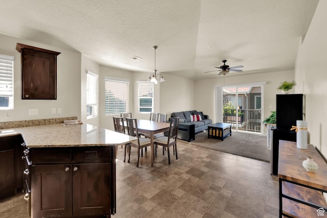 8264 S Resaca Dr Unit K9, Sandy, UT 84070 - kitchen with dark brown cabinetry, a ceiling fan, open floor plan, pendant lighting, and light stone countertops