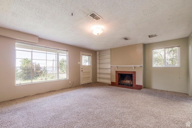 420 E 12th Ave, Salt Lake City, UT 84103 - unfurnished living room featuring a fireplace, healthy amount of natural light, a textured ceiling, carpet, and built in shelves