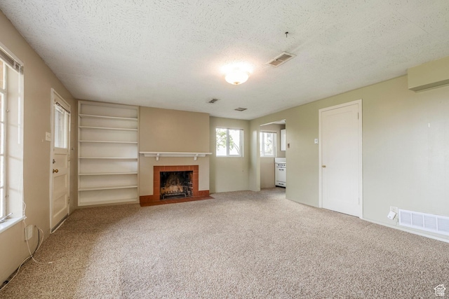 420 E 12th Ave, Salt Lake City, UT 84103 - unfurnished living room with a textured ceiling, a tile fireplace, built in shelves, and carpet