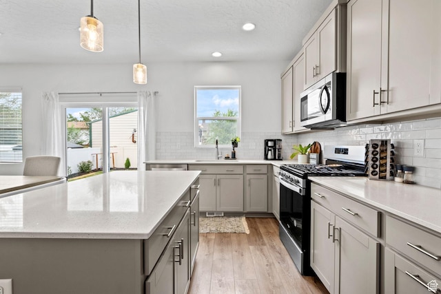 1162 W 1100 S, Clearfield, UT 84015 - kitchen with appliances with stainless steel finishes, gray cabinetry, light wood finished floors, decorative backsplash, and a kitchen island