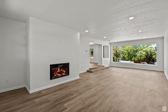 1175 E 900 N, Lehi, UT 84043 - unfurnished living room featuring wood finished floors, recessed lighting, a textured ceiling, and a glass covered fireplace