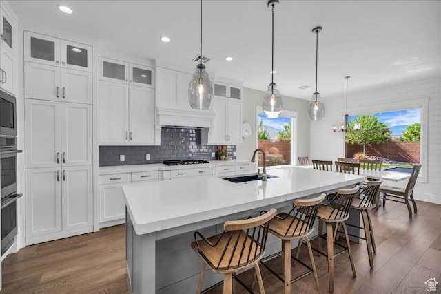2249 E Fieldstone Cir, St George, UT 84790 - kitchen with dark wood-style flooring, a kitchen island with sink, decorative backsplash, white cabinets, and recessed lighting