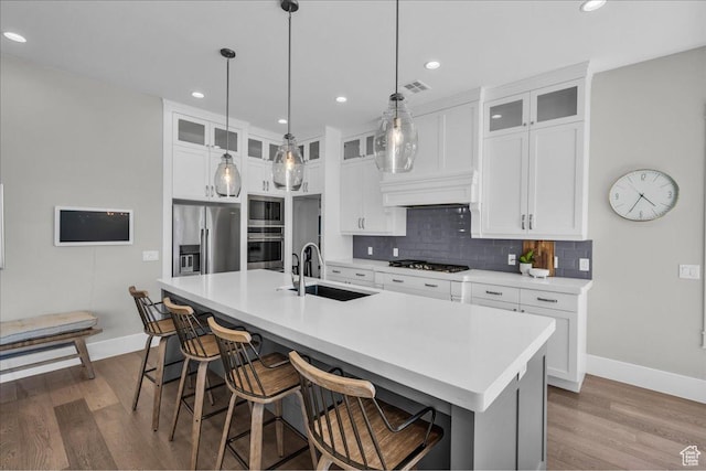 2249 E Fieldstone Cir, St George, UT 84790 - kitchen featuring stainless steel appliances, wood finished floors, decorative backsplash, a center island with sink, and a kitchen breakfast bar