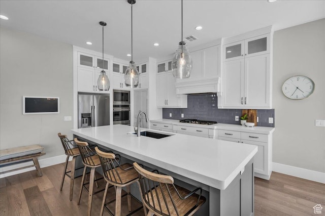 2249 E Fieldstone Cir, St George, UT 84790 - kitchen with stainless steel appliances, dark wood-style flooring, tasteful backsplash, an island with sink, and white cabinetry