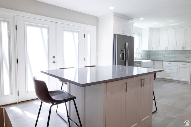 11089 S Justin Dr, Sandy, UT 84092 - kitchen featuring stainless steel fridge, a kitchen breakfast bar, white cabinets, backsplash, and a kitchen island