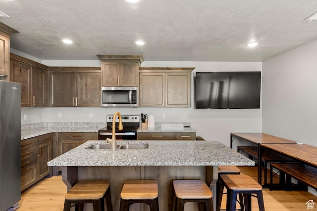 130 W Seasons Loop Upper, Upper, Garden City, UT 84028 - kitchen with stainless steel appliances, light wood-type flooring, a kitchen bar, light stone counters, and a textured ceiling