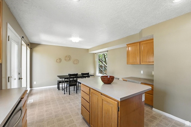 1298 Eastridge Cir, Logan, UT 84321 - kitchen featuring light floors, light countertops, a textured ceiling, a kitchen island, and dishwasher