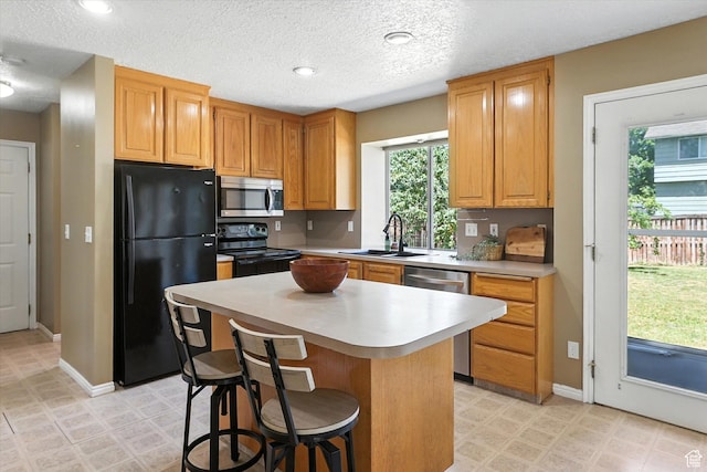1298 Eastridge Cir, Logan, UT 84321 - kitchen with black appliances, a center island, light countertops, a breakfast bar, and a textured ceiling