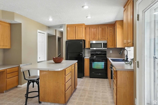 1298 Eastridge Cir, Logan, UT 84321 - kitchen with black appliances, light countertops, a center island, a textured ceiling, and a kitchen bar