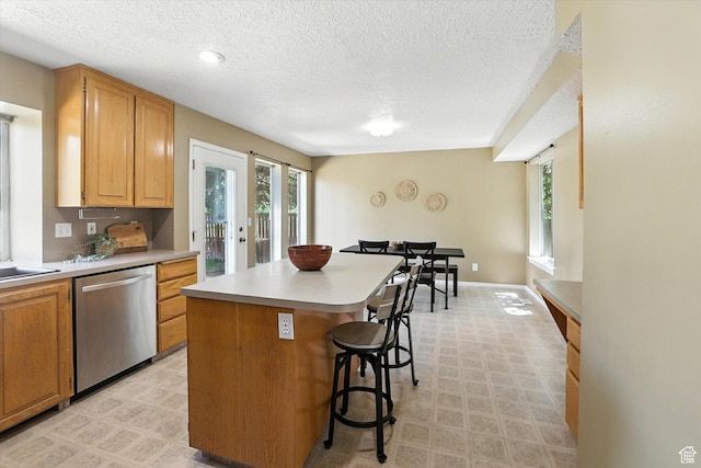 1298 Eastridge Cir, Logan, UT 84321 - kitchen with dishwasher, a textured ceiling, a kitchen bar, light countertops, and a kitchen island