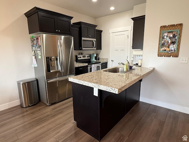 7579 N Cottage Ln, Eagle Mountain, UT 84005 - kitchen featuring stainless steel appliances, a peninsula, dark wood-style flooring, light countertops, and a kitchen bar