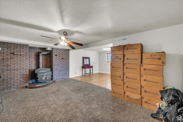 120 N Scenic Dr E, Washington, UT 84780 - living room with a wood stove, carpet floors, ceiling fan, a textured ceiling, and brick wall