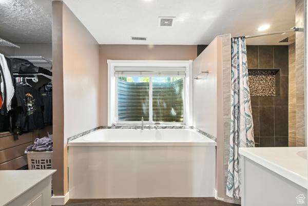 13032 S 1300 W, Riverton, UT 84065 - full bathroom featuring a garden tub, vanity, a spacious closet, a tile shower, and wood finished floors