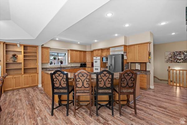 13032 S 1300 W, Riverton, UT 84065 - kitchen featuring appliances with stainless steel finishes, light wood-style floors, a kitchen island, a breakfast bar, and recessed lighting