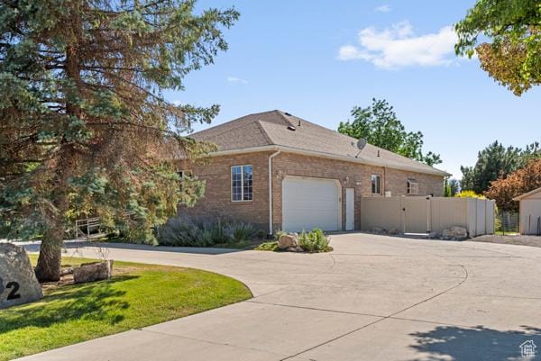 13032 S 1300 W, Riverton, UT 84065 - view of side of home featuring driveway, a garage, brick siding, and a gate