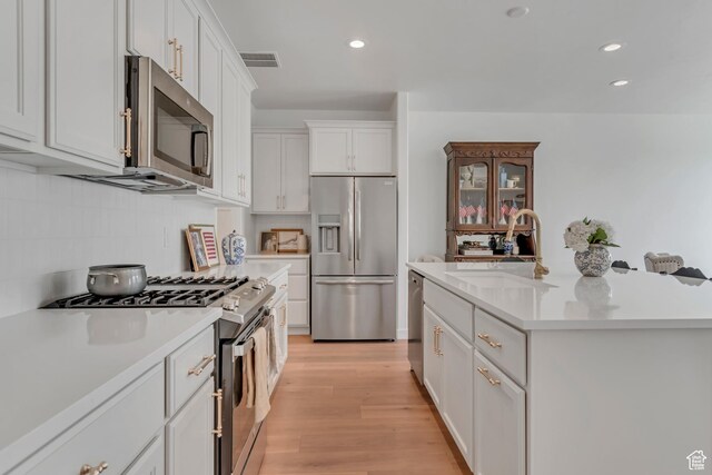 169 E Volunteer Dr, Spanish Fork, UT 84660 - kitchen featuring appliances with stainless steel finishes, light countertops, white cabinetry, decorative backsplash, and a center island with sink