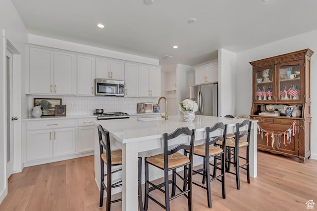 169 E Volunteer Dr, Spanish Fork, UT 84660 - kitchen with appliances with stainless steel finishes, light wood-style floors, a breakfast bar area, decorative backsplash, and recessed lighting