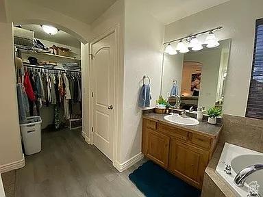 3462 Heyward Ct, Eagle Mountain, UT 84043 - bathroom featuring vanity, a garden tub, wood finished floors, and a walk in closet