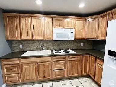 3462 Heyward Ct, Eagle Mountain, UT 84043 - kitchen with white appliances, tasteful backsplash, dark countertops, light tile patterned floors, and recessed lighting