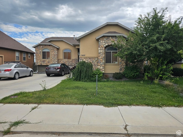 3462 Heyward Ct, Eagle Mountain, UT 84043 - view of front of house with stucco siding, stone siding, a front lawn, and driveway