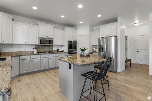 1692 N Sage Ln, Saratoga Springs, UT 84045 - kitchen with stainless steel appliances, a breakfast bar area, white cabinets, light stone countertops, and recessed lighting
