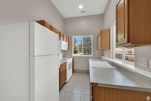 3112 N Pelican Dr, Farr West, UT 84404 - kitchen with white appliances, light tile patterned floors, brown cabinetry, and light countertops