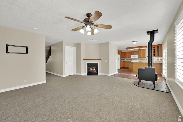 3112 N Pelican Dr, Farr West, UT 84404 - unfurnished living room featuring a wood stove, carpet, a ceiling fan, and a textured ceiling