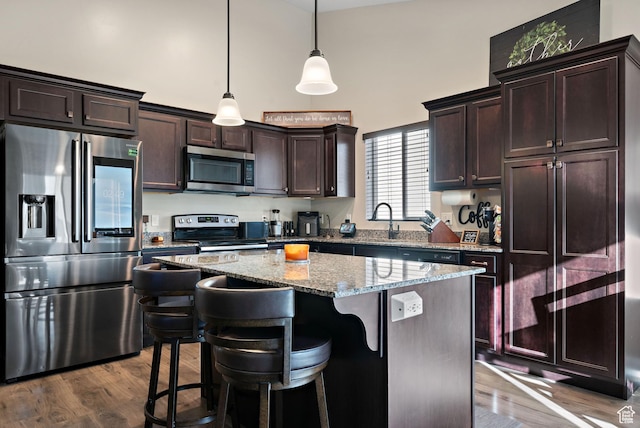 1769 W Valcrest Dr, Saratoga Springs, UT 84045 - kitchen with stainless steel appliances, a towering ceiling, dark brown cabinets, light stone counters, and a center island