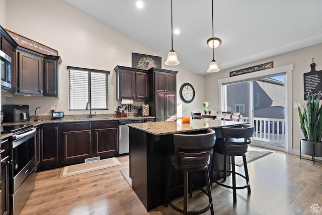 1769 W Valcrest Dr, Saratoga Springs, UT 84045 - kitchen with appliances with stainless steel finishes, light stone countertops, a center island, a breakfast bar, and light wood finished floors