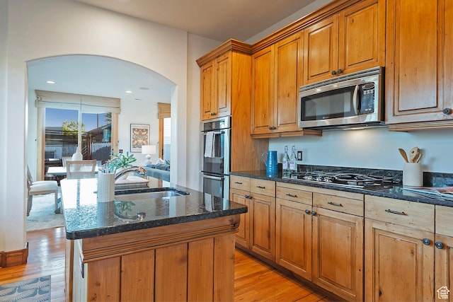 427 N J St E, Salt Lake City, UT 84103 - kitchen with appliances with stainless steel finishes, arched walkways, light wood-type flooring, dark stone countertops, and a center island