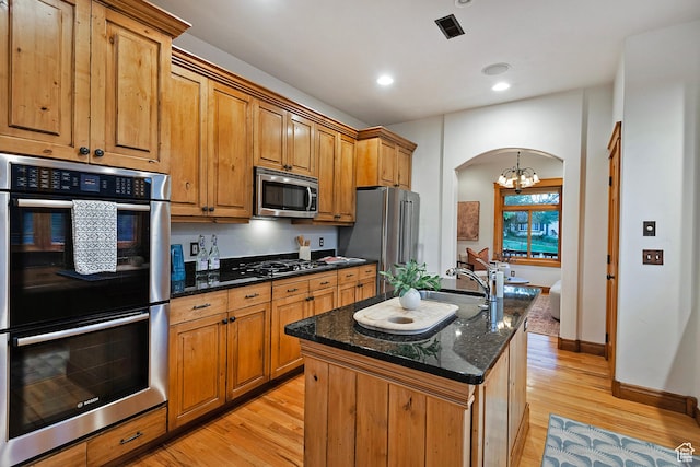 427 N J St E, Salt Lake City, UT 84103 - kitchen with appliances with stainless steel finishes, a chandelier, light wood-type flooring, dark stone counters, and arched walkways