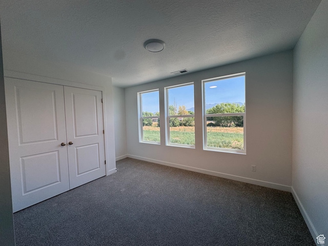 1456 N 1875 W Unit 147, Layton, UT 84041 - unfurnished bedroom with dark colored carpet, a closet, and a textured ceiling