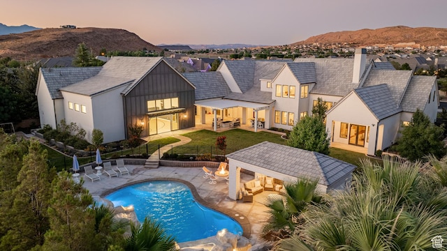 2916 S 300 E, Washington, UT 84780 - back of property at dusk with outdoor lounge area, a fenced backyard, a mountain view, and a patio
