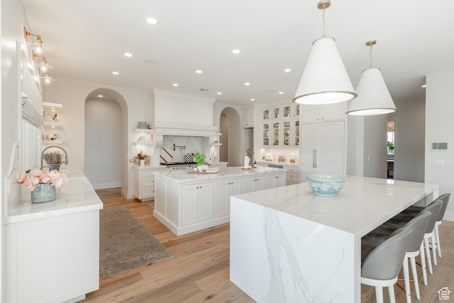 2916 S 300 E, Washington, UT 84780 - kitchen with arched walkways, a spacious island, light wood-type flooring, recessed lighting, and white cabinetry