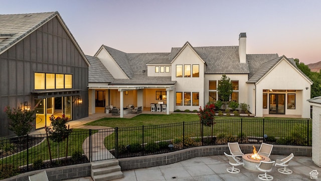 2916 S 300 E, Washington, UT 84780 - back of house at dusk featuring a patio, a fenced front yard, a chimney, and board and batten siding