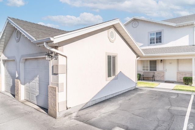 287 E 2300 N Unit 30, North Ogden, UT 84414 - view of side of home with stucco siding, a shingled roof, an attached garage, and brick siding