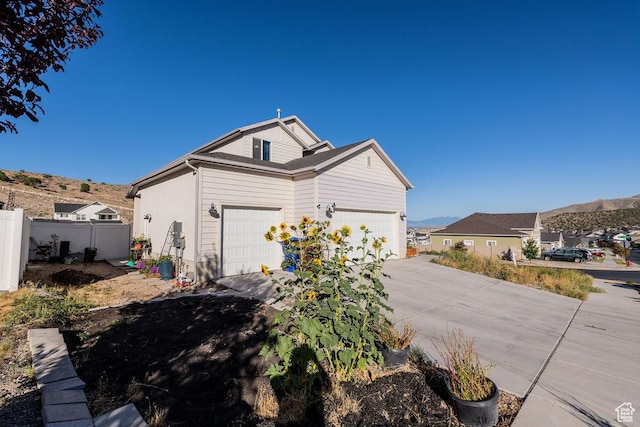 7390 N Pawnee Rd, Eagle Mountain, UT 84005 - view of home's exterior featuring concrete driveway, a mountain view, and a garage