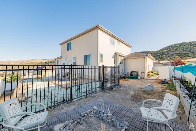 7390 N Pawnee Rd, Eagle Mountain, UT 84005 - rear view of house with a mountain view, a fenced backyard, stucco siding, and a swimming pool