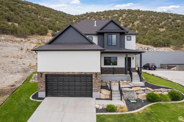 3873 E S Pass Cv, Eagle Mountain, UT 84005 - view of front of home featuring covered porch, driveway, an attached garage, stone siding, and a front yard