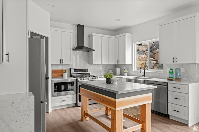 3873 E S Pass Cv, Eagle Mountain, UT 84005 - kitchen with appliances with stainless steel finishes, wall chimney range hood, white cabinets, light wood-style floors, and decorative backsplash