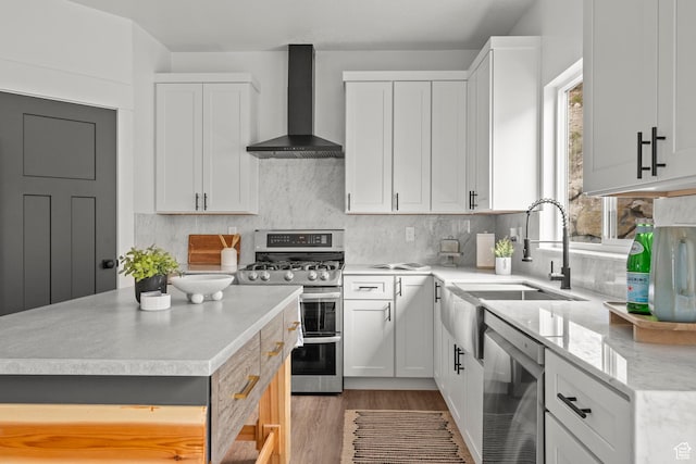 3873 E S Pass Cv, Eagle Mountain, UT 84005 - kitchen featuring wall chimney exhaust hood, stainless steel appliances, light wood-style flooring, tasteful backsplash, and white cabinetry